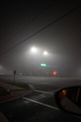 Street lights illuminate an empty intersection on a foggy night