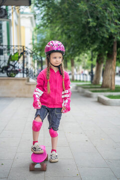 A little girl with pink skateboard in the park.