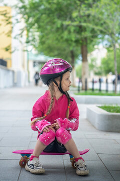 A little girl with pink skateboard in the park.