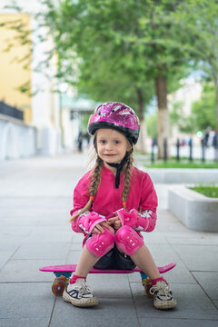 A little girl with pink skateboard in the park.