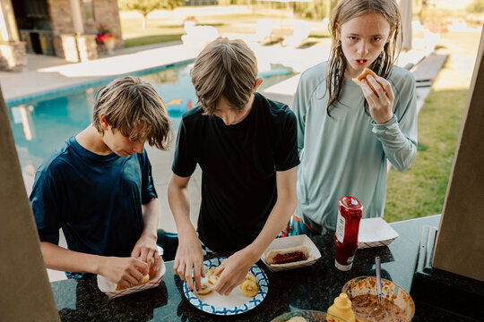 Teenagers preparing hot dogs and fruit by the pool