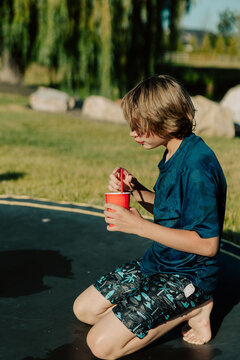 Boy drinking from red plastic cup while on trampoline