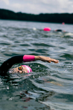 Swimmer with swim cap and buoy in open water lake, summer training