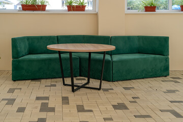 A welcoming contemporary indoor lounge space featuring a comfortable emerald green velvet corner...