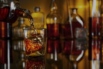 Pouring whiskey from a bottle into a glass.