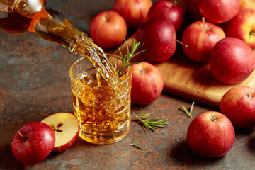 Apple cider is poured from a bottle into a glass.