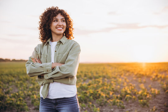 Young agronomist smiling and posing in cultivated soybean field at sunset