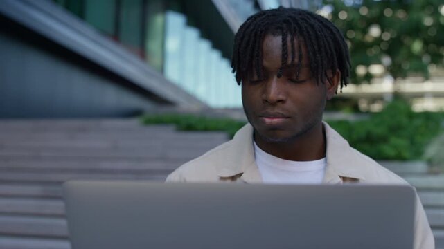 Focused Man Working on Laptop Outside in City