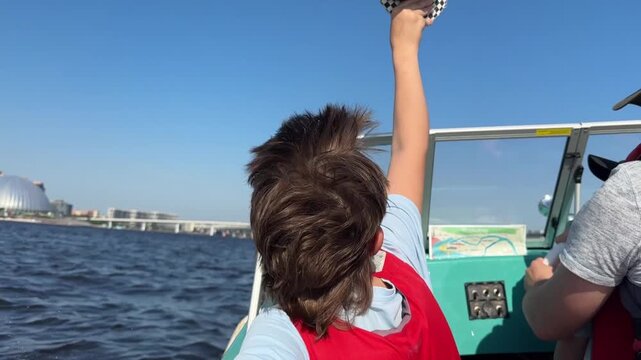 boy enjoys riding on motor boat with his father lon Neva river, Saint Petersburg