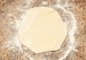 A doughnut is being rolled out on a counter