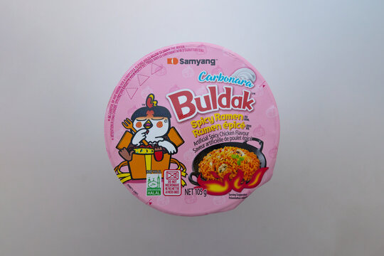 Calgary, Alberta, Canada. Jul 18, 2025. A flat lay features a Samyang Buldak Carbonara Spicy Ramen cup, showcasing its vibrant pink design and appetizing noodle illustration.