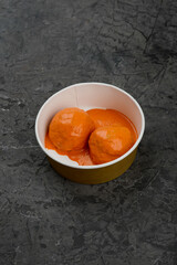 two large meatballs in tomato sauce in a disposable container