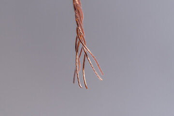 Minimalistic image of twisted bare copper wire tip placed on a white surface.