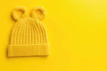 Bright yellow knitted beanie with large ear flaps on a solid yellow background