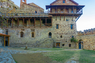 Monastery courtyard. Carved railings, balconies and stairs. Stone paths and walls. Tiled roof and...