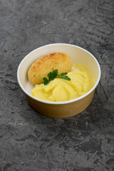 Mashed potatoes with cutlet in disposable dishes on a gray background
