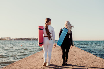 Yoga Women Beach Walking with Yoga Mats on Pier at Sunset