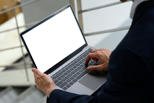 Close up of businessman using laptop with blank screen in urban setting