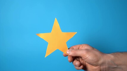 Hand Holding a Yellow Star on a Blue Background Symbolizing Success Positive Feedback and Quality Evaluation in a Simple and Minimalist Composition