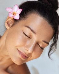 Relaxed Woman With Glowing Hydrated Skin And Flower In Hair Smiling Softly