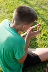 Boy gently holding a small green and yellow bird outdoors.