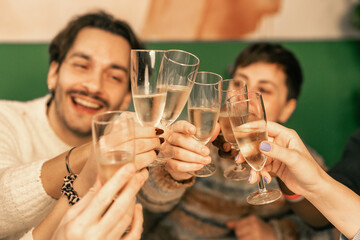 Happy friends laughing and toasting with champagne at a festive holiday party. A diverse group of...