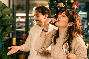 Woman eating an appetizer of cured meat at a festive holiday party. A group of friends socializing and enjoying food and wine during a Christmas dinner at home.