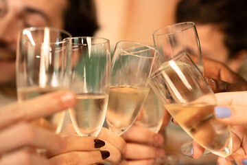 Close-up of friends making a celebratory toast with champagne glasses.