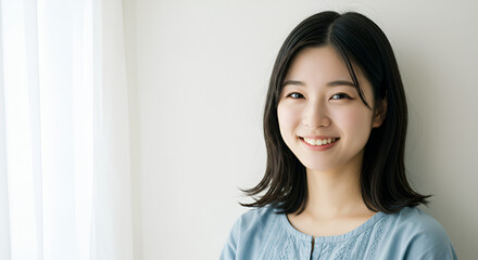 Portrait of a beautiful young Asian woman smiling against a simple white background