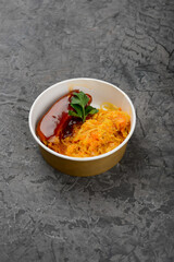 stewed cabbage with meat in sauce in a single-row dish on a gray background