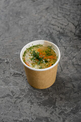 Soup in a disposable container on a gray background