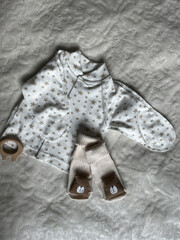A set of clothes for a newborn baby lies neatly on a light blanket. Preparing for the arrival of a...
