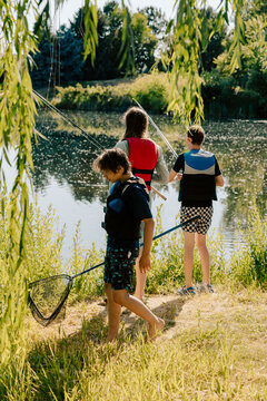 Friends fishing with rods and landing net in lake