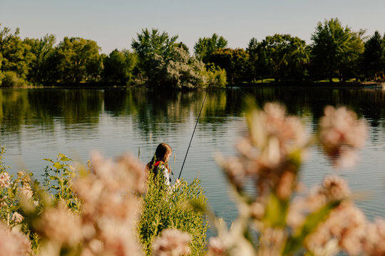 Young boy fishing in a lake surrounded by lush greenery
