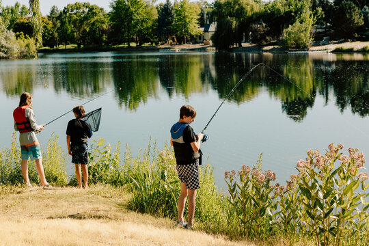 Three young boys fishing on a lake shore during vacation