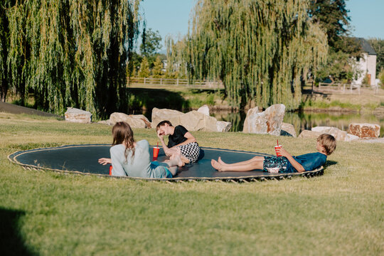 Teen boys relaxing on trampoline by the lake