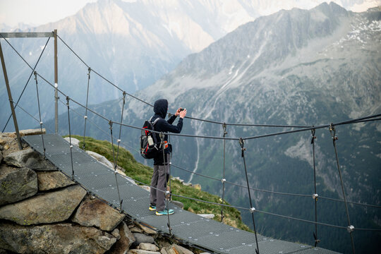 Man taking photo with smartphone on suspension bridge in Austrian Alps