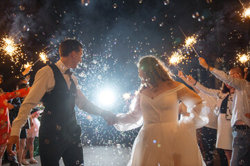 Couple celebrates wedding with sparklers and bubbles at night