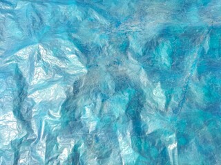 Obraz premium Old blue plastic sheet with rough, uneven surface for material protection, wrinkled blue plastic covering sheet for goods, abstract blue background with uneven wrinkles