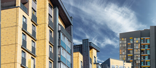 Residential complex in cityscape. Modern yellow and gray brick building with panel facade, balconies