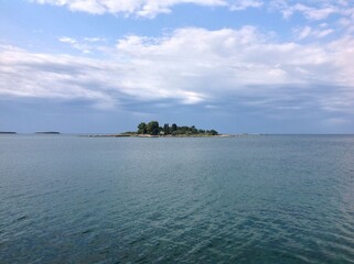 Serene island view with blue waters and cloudy sky.