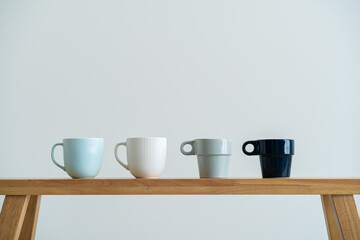 Minimalist cups on a wooden bench against white wall