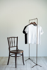 Minimal clothing setup with wooden chair and monochrome T-shirts