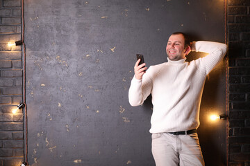 A man in a white sweater listens to music