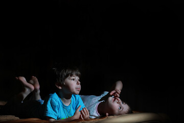 Small children in a dark room watching TV