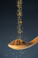 Aromatic spice mixture fall from above onto a wooden spoon, great for gourmet cooking and flavor...