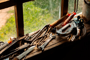 There are old tools on the windowsill: wrenches, a hammer, a chisel, a knife, screwdrivers....