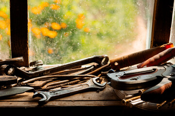 On the table by the window lie old tools: wrenches, screwdrivers, a hammer, a chisel and a knife....