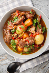 Beef stew Semur Daging with potatoes, carrot and a rich sweet-spiced soy sauce-based broth closeup in the bowl on the table. Vertical top view from above