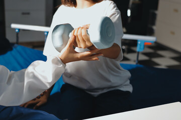 Unrecognizable uses blue hand weight during physical therapy session